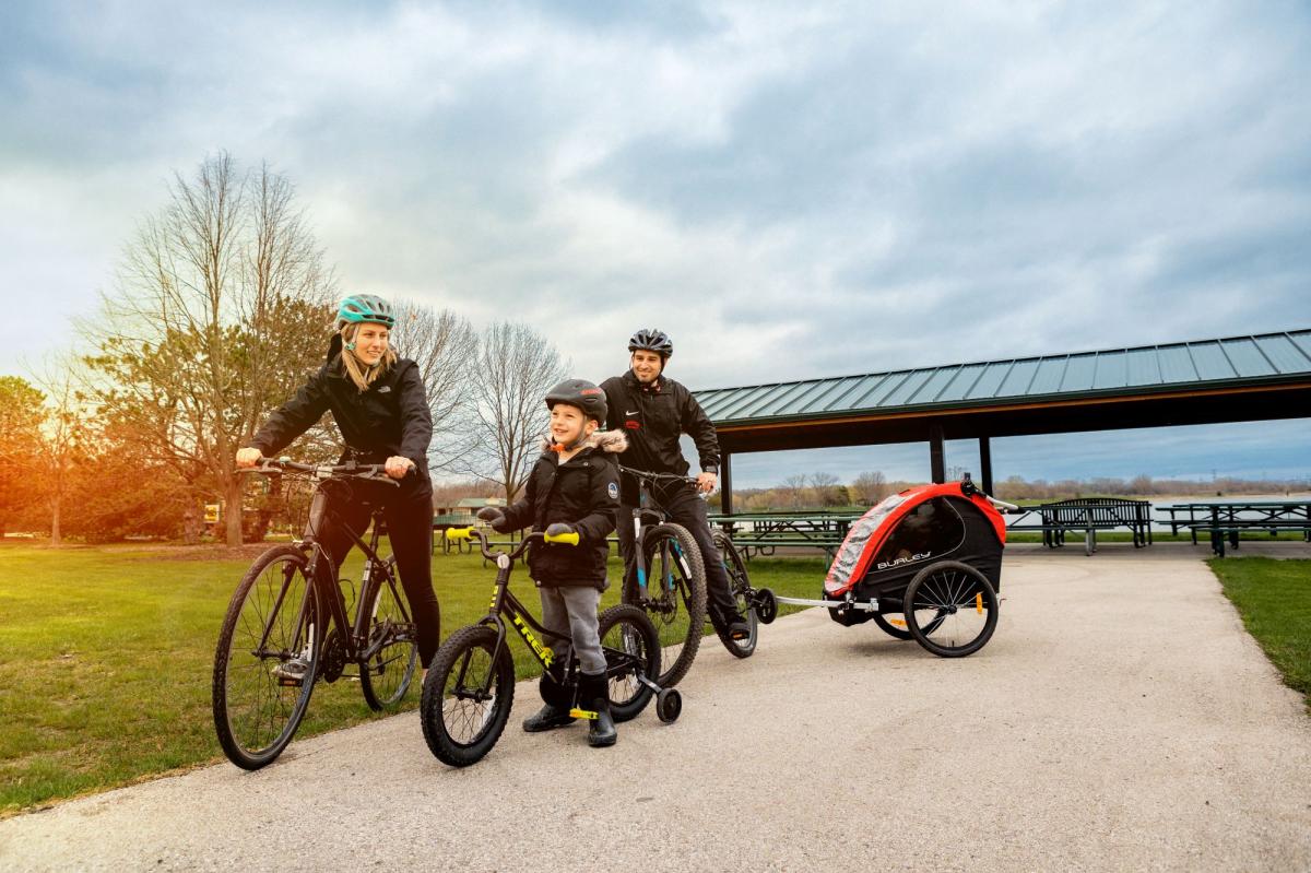 A family out for a bicycle ride beside a lakeside pavilion
